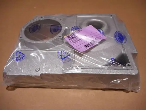 Transparente Verpackung mit einem silbernen Gehäuse von Remeha, das über zwei Öffnungen verfügt. Sichtbar sind blaue Symbole und ein Etikett mit Produktinformationen.